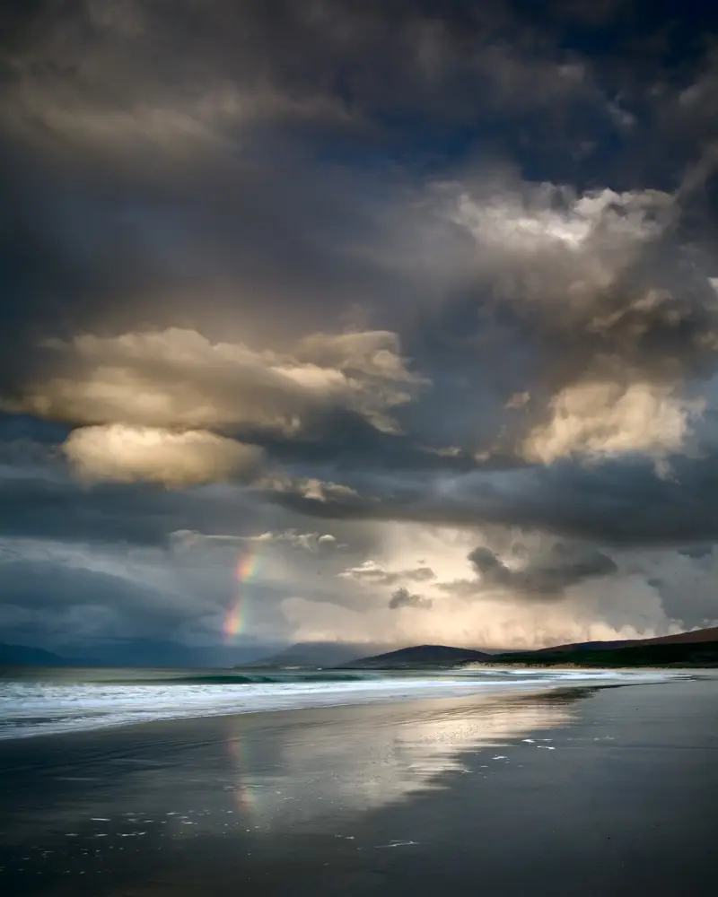 a beach with a rainbow in the sky. cloud nature water outdoor sky rainbow horizon calm landscape beach clouds ocean sunset seascape
