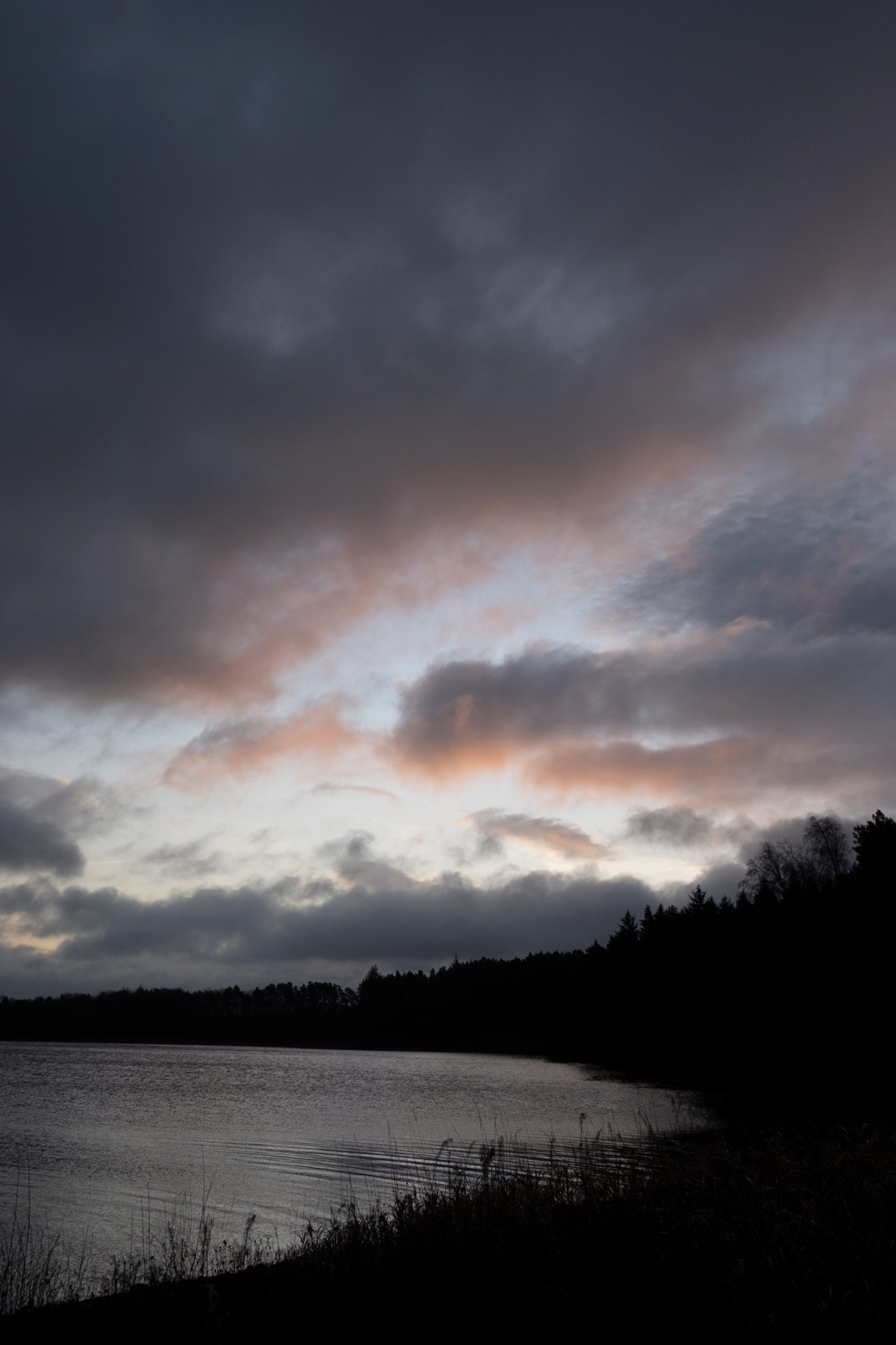 a group of clouds in the sky over a body of water. sky outdoor cloud clouds lake tree cloudy landscape water nature mountain dark day distance