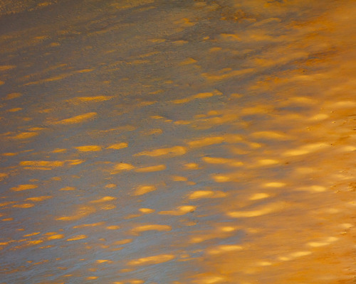 Reflections:  a body of water with orange and yellow clouds