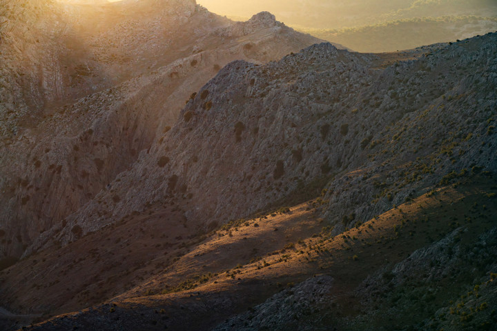 a rocky hillside with a dirt road. mountain outdoor sky landscape geology badlands sunrise terrain wadi mountain range highland massif summit ridge makhtesh nature ground sunset sun