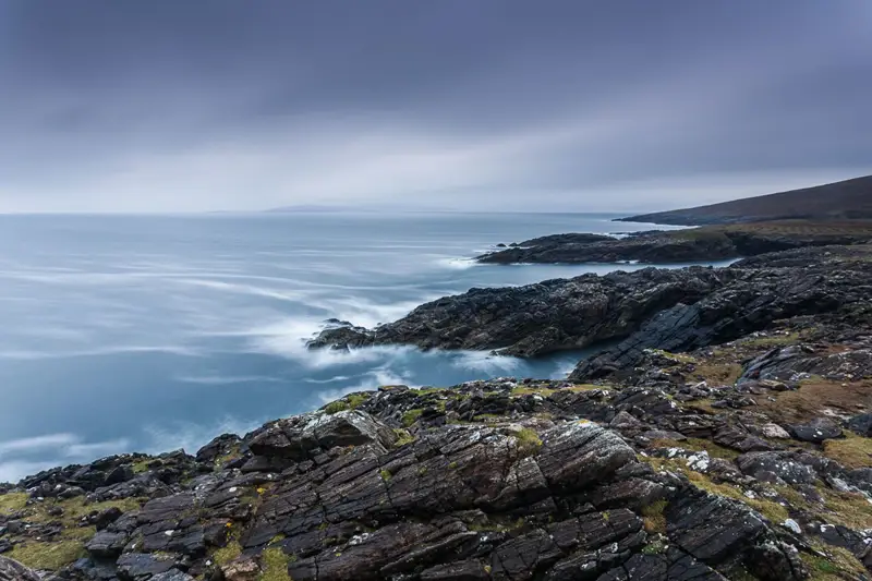 a rocky beach next to the ocean. outdoor sky rock beach water landscape rocky nature coast ocean sea mountain seascape hill