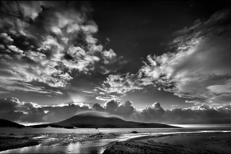a beach with a body of water and mountains in the background with Pearl Harbor in the background. landscape nature sky black and white outdoor beach horizon water cloud cumulus monochrome seascape clouds sunset mountain ocean
